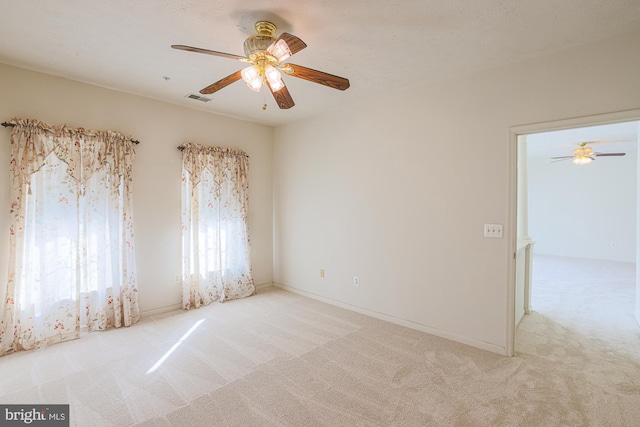 empty room featuring ceiling fan and light carpet