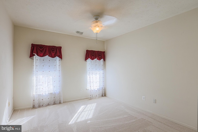 empty room featuring ceiling fan, a textured ceiling, and light carpet