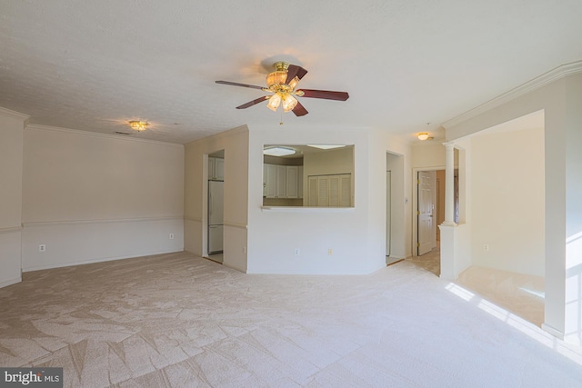 unfurnished living room featuring ornate columns, ceiling fan, light colored carpet, and crown molding