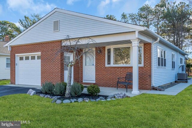 view of front of home featuring central air condition unit, covered porch, a front yard, and a garage