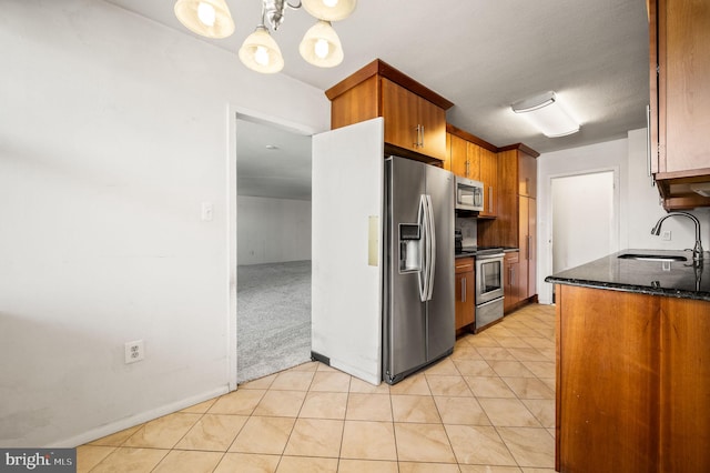 kitchen with appliances with stainless steel finishes, light colored carpet, pendant lighting, sink, and an inviting chandelier