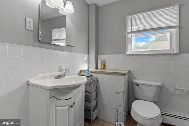 bathroom with vanity, a baseboard heating unit, tile patterned floors, toilet, and tile walls