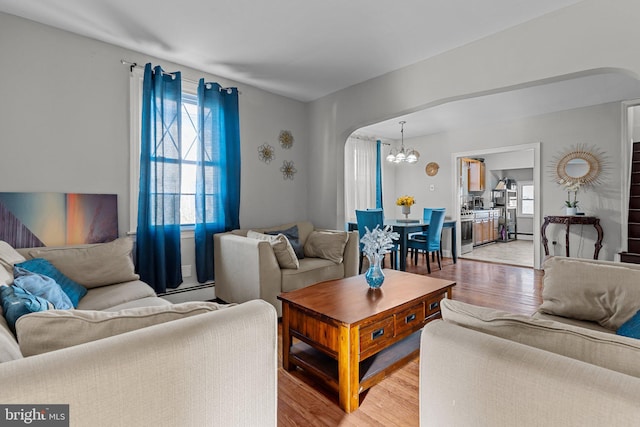 living room featuring light hardwood / wood-style floors, an inviting chandelier, and a baseboard heating unit