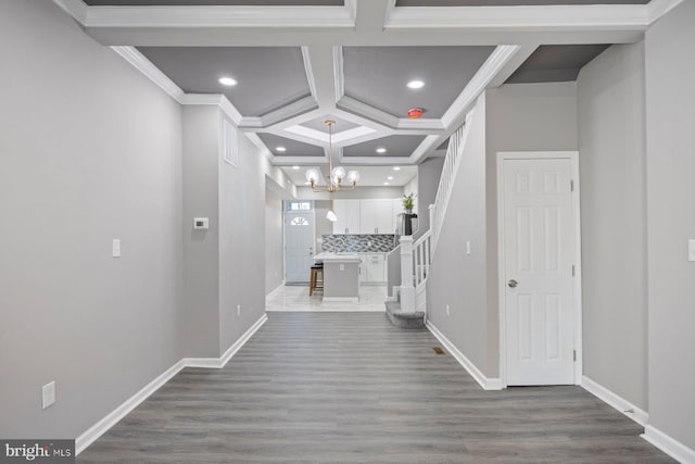 hall featuring crown molding, hardwood / wood-style floors, coffered ceiling, and a notable chandelier