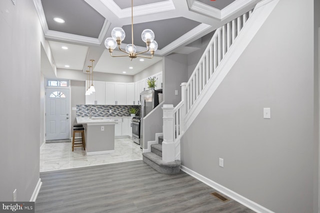 entryway with sink, coffered ceiling, light hardwood / wood-style flooring, a chandelier, and ornamental molding