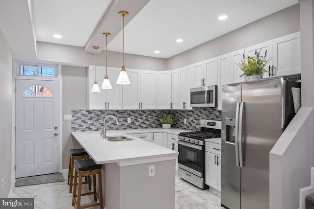 kitchen featuring a kitchen breakfast bar, kitchen peninsula, sink, appliances with stainless steel finishes, and white cabinetry