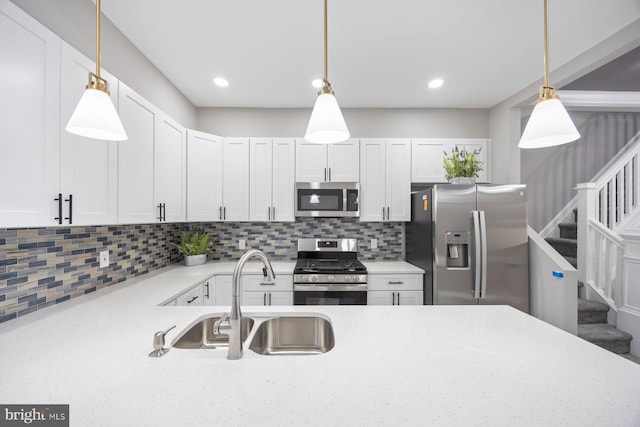 kitchen with appliances with stainless steel finishes, tasteful backsplash, sink, white cabinetry, and hanging light fixtures