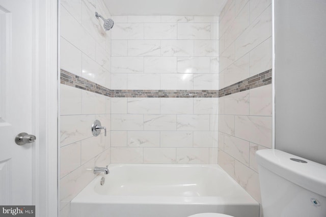 bathroom featuring tiled shower / bath combo and toilet