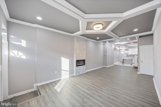 unfurnished living room with a premium fireplace, ornamental molding, coffered ceiling, and hardwood / wood-style flooring