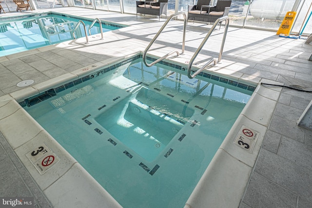 view of swimming pool featuring a jacuzzi and a patio