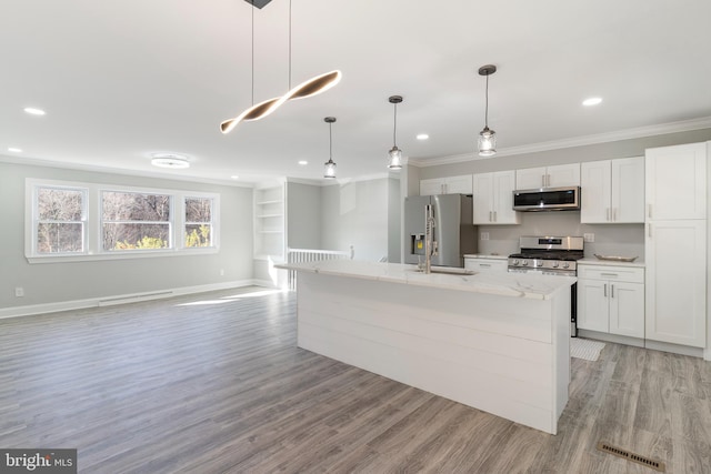 kitchen featuring white cabinetry, hanging light fixtures, a center island with sink, appliances with stainless steel finishes, and light wood-type flooring