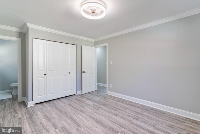 unfurnished bedroom with a closet, ornamental molding, connected bathroom, and light hardwood / wood-style flooring