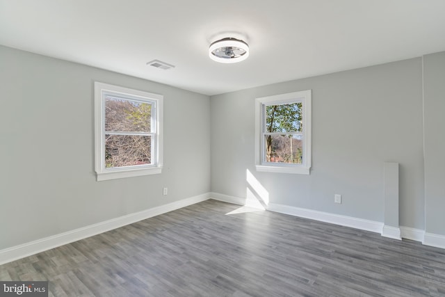 unfurnished room featuring dark hardwood / wood-style flooring and plenty of natural light