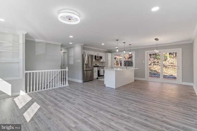 kitchen with white cabinets, appliances with stainless steel finishes, light wood-type flooring, and hanging light fixtures