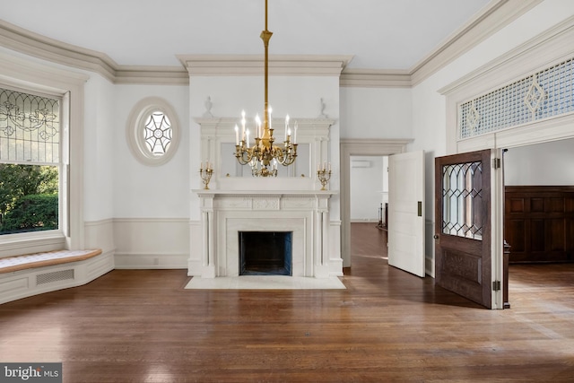 unfurnished living room with crown molding, a fireplace, dark wood-type flooring, and a notable chandelier