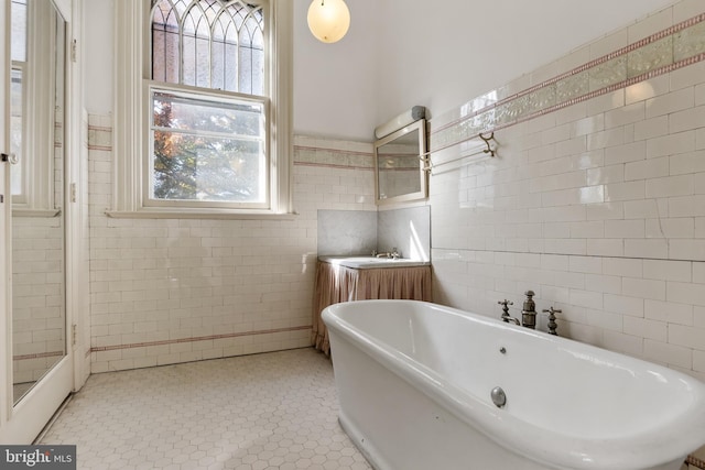 bathroom featuring plenty of natural light, a bathtub, and tile walls