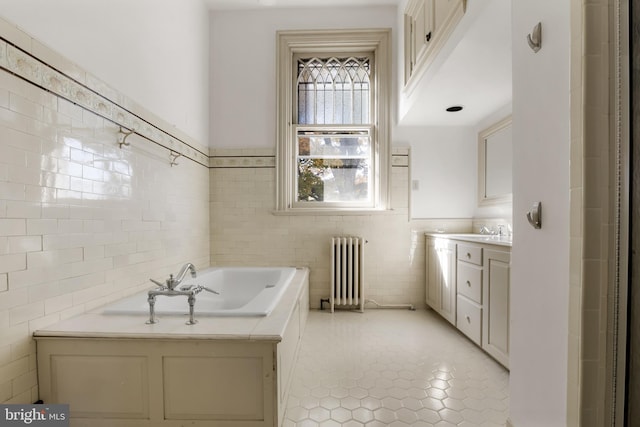 bathroom featuring a tub to relax in, tile patterned floors, radiator, vanity, and tile walls