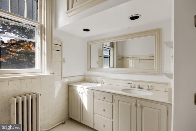 bathroom featuring vanity, radiator heating unit, and tile walls