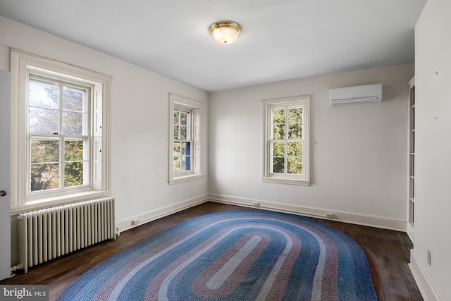 spare room featuring a healthy amount of sunlight, a wall unit AC, dark wood-type flooring, and radiator