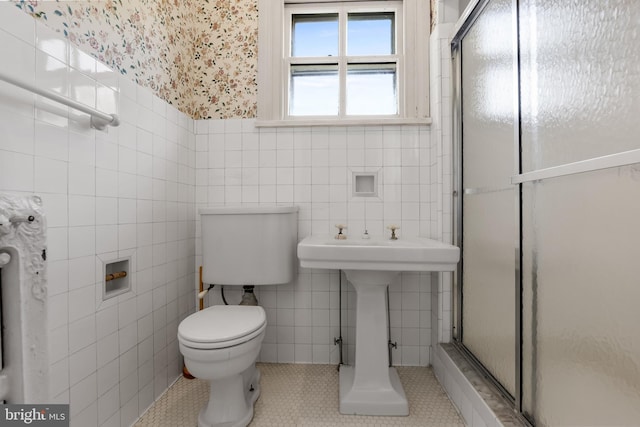 bathroom with toilet, tile patterned flooring, tile walls, and walk in shower