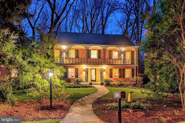 view of front of house featuring a balcony and a front lawn