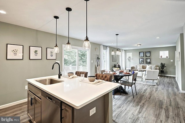 kitchen with dishwasher, sink, a kitchen island with sink, and decorative light fixtures