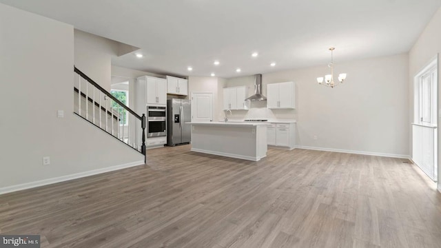 805 Long Meadow Dr, Fredericksburg, VA 22406 - kitchen featuring stainless steel appliances, wall chimney exhaust hood, open floor plan, a chandelier, and light wood-type flooring