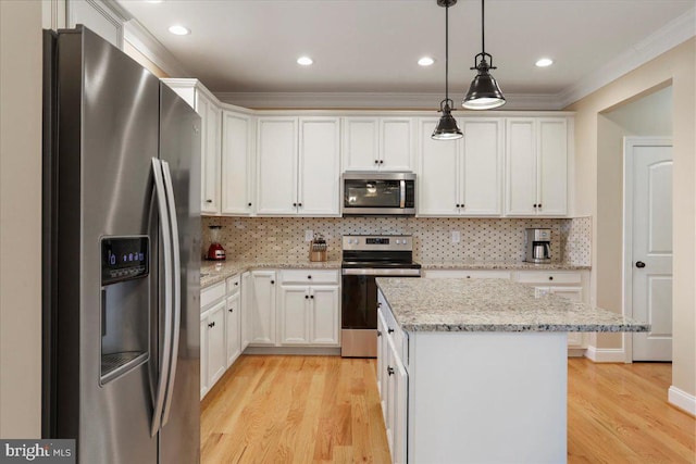 kitchen featuring decorative light fixtures, a kitchen island, backsplash, white cabinets, and appliances with stainless steel finishes