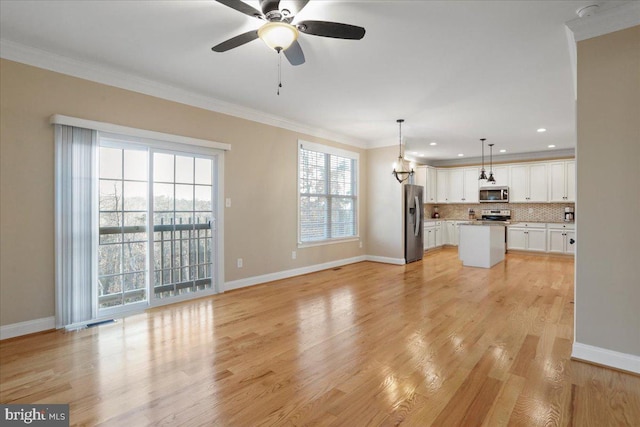 unfurnished living room featuring light hardwood / wood-style floors, ceiling fan, crown molding, and a wealth of natural light