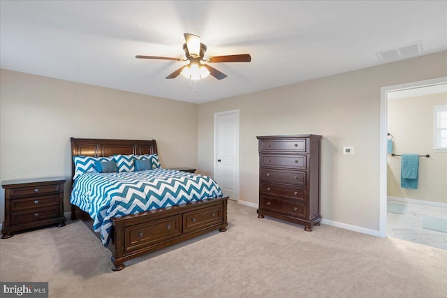 bedroom with ensuite bathroom, light colored carpet, and ceiling fan