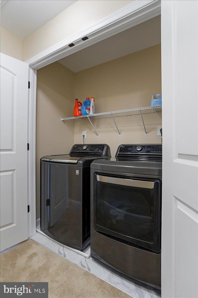 washroom with washing machine and clothes dryer and light carpet