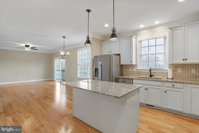 kitchen with pendant lighting, a kitchen island, white cabinetry, appliances with stainless steel finishes, and sink