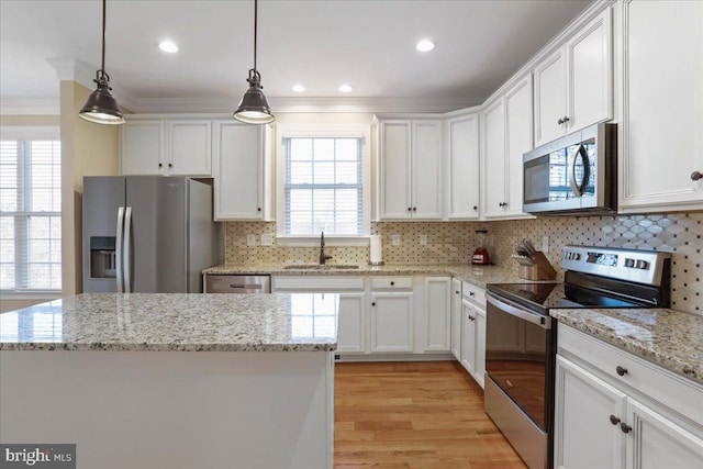 kitchen featuring a center island, hanging light fixtures, white cabinets, appliances with stainless steel finishes, and sink