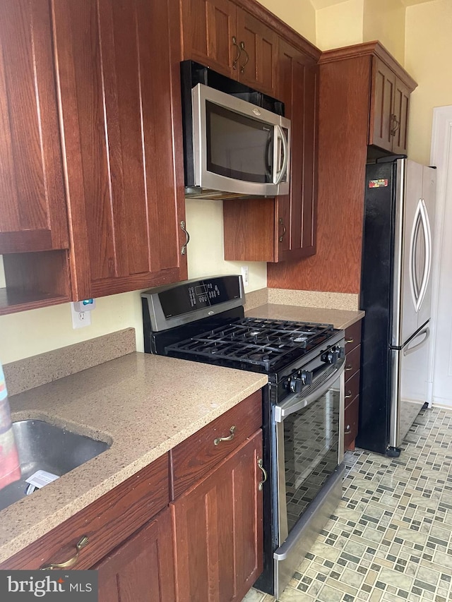 kitchen with light stone countertops, sink, and appliances with stainless steel finishes