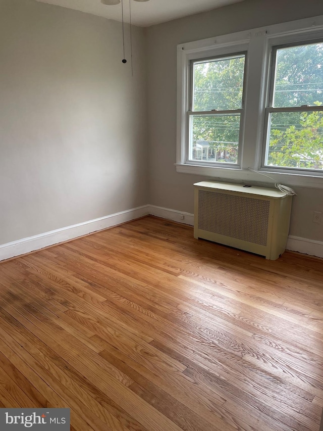 empty room featuring light wood-type flooring and radiator