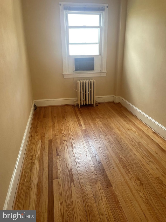 empty room with light hardwood / wood-style flooring and radiator