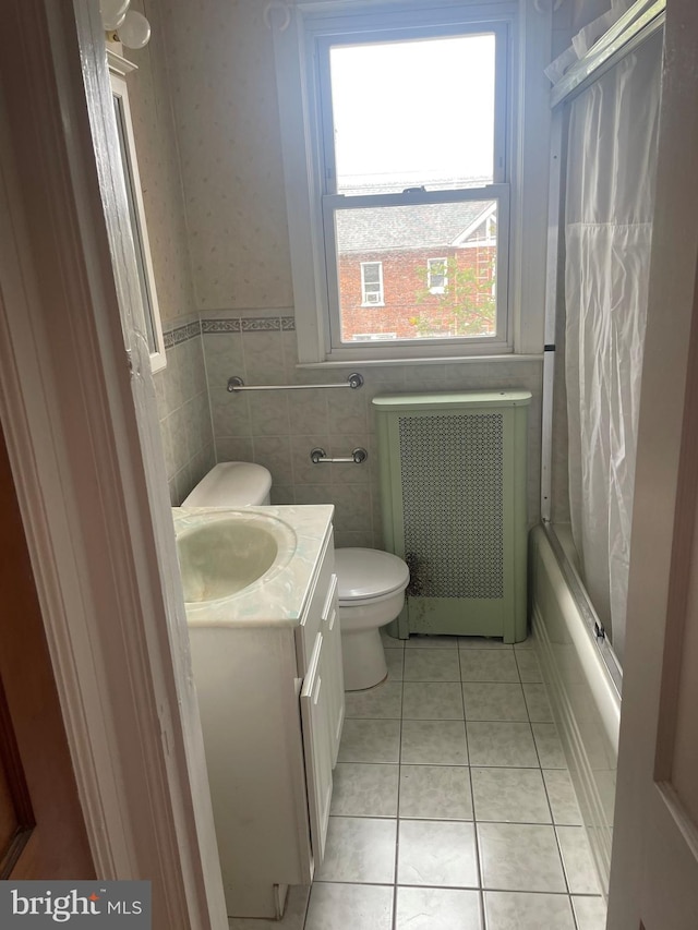 full bathroom featuring tile patterned floors, radiator, vanity, tile walls, and toilet