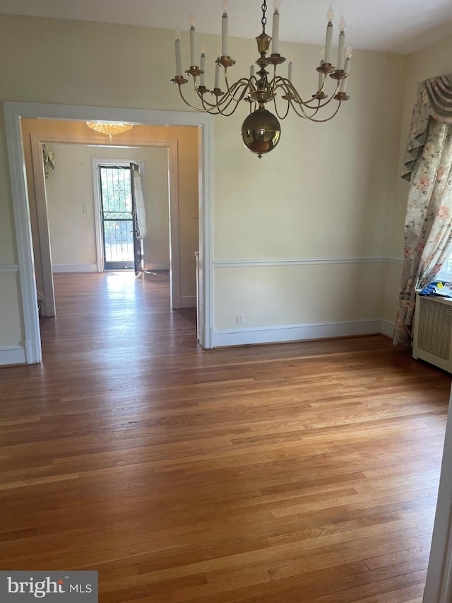 unfurnished dining area featuring light wood-type flooring, radiator heating unit, and a chandelier