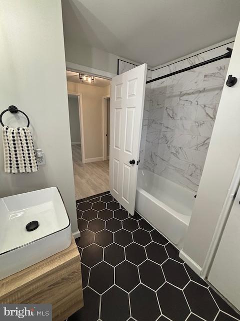 bathroom featuring wood-type flooring and tiled shower / bath