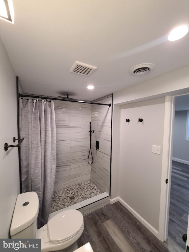 bathroom featuring hardwood / wood-style floors, curtained shower, and toilet