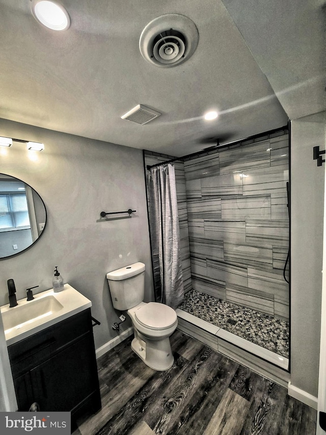 bathroom featuring a shower with shower curtain, hardwood / wood-style floors, vanity, and toilet