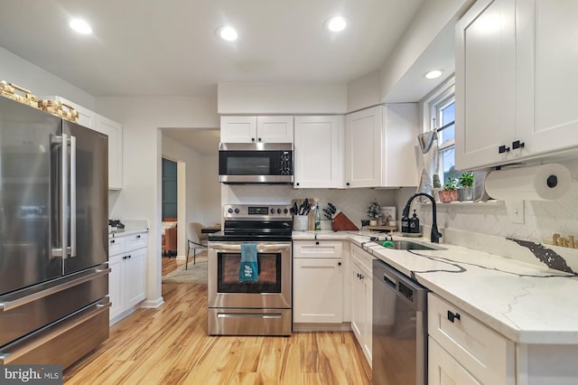 kitchen with white cabinets, light wood-type flooring, stainless steel appliances, and sink