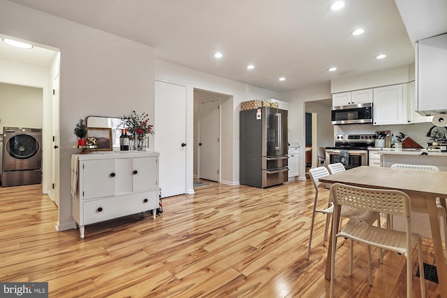 kitchen with light wood-type flooring, tasteful backsplash, washer / dryer, white cabinetry, and stainless steel appliances