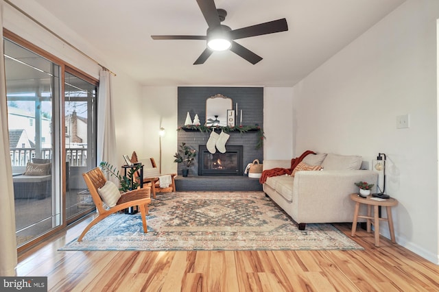 living room with hardwood / wood-style floors, ceiling fan, and a brick fireplace