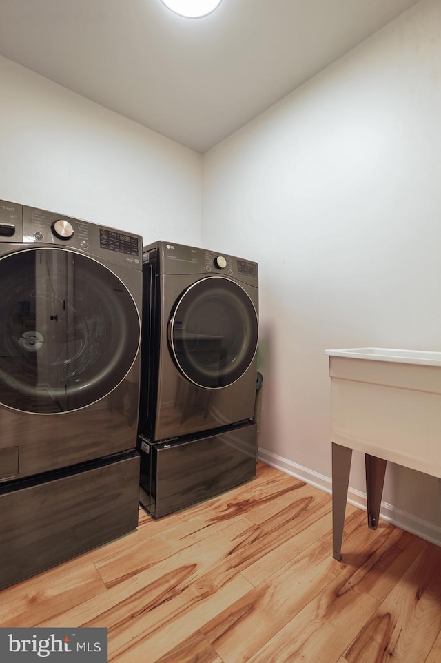 clothes washing area featuring hardwood / wood-style flooring and washing machine and clothes dryer