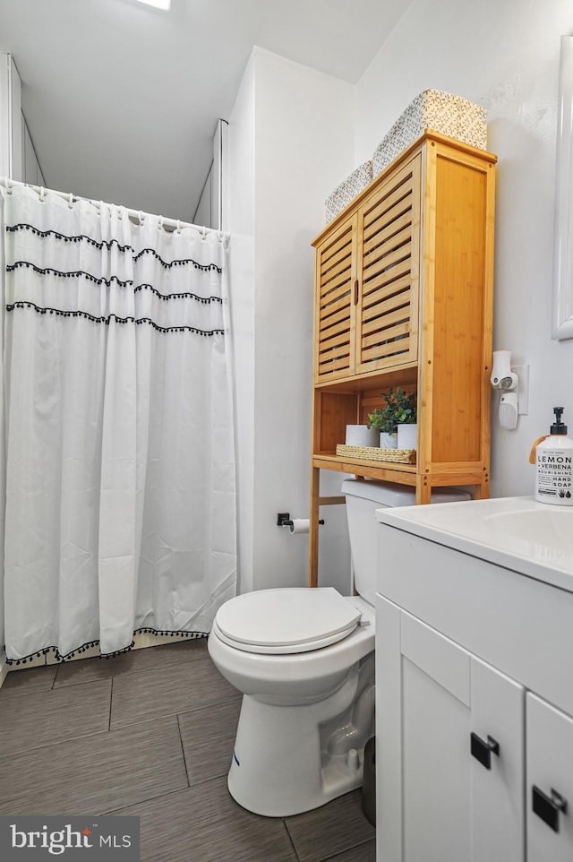 bathroom featuring a shower with shower curtain, vanity, toilet, and tile patterned flooring