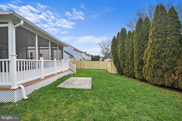 view of yard featuring a sunroom, a patio, and a storage unit