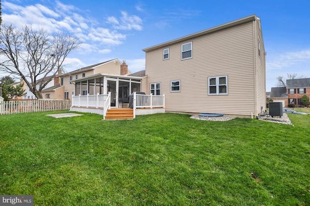 back of house featuring a lawn, a sunroom, cooling unit, and a deck