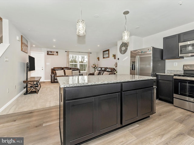 kitchen featuring a center island, light stone countertops, stainless steel appliances, and hanging light fixtures