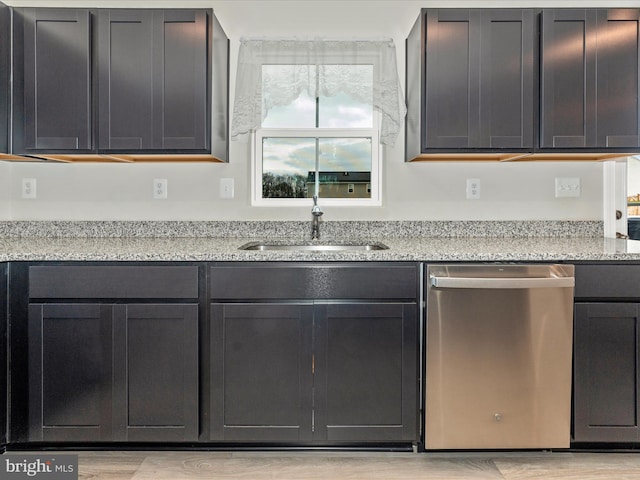 kitchen featuring dishwasher, light stone counters, and sink